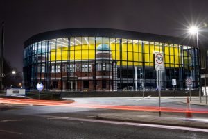 Photograph showing the glass frontage of the Danum building lit up at night