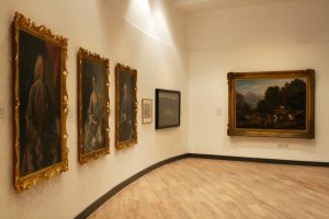 Photograph showing three portraits hanging on a white wall