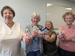 Four women with crafted peg dolls